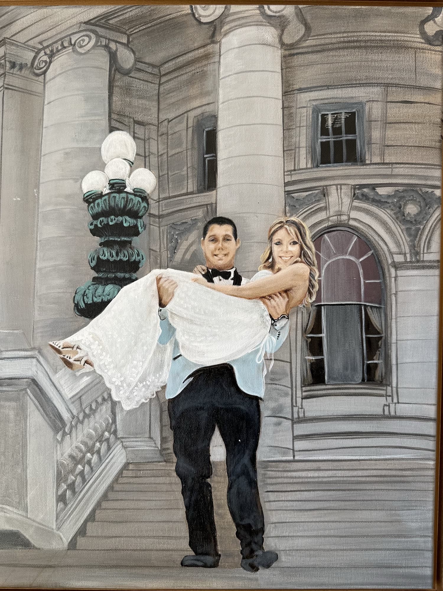 Framed live wedding painting of a groom carrying his bride on the steps of the Wisconsin State Capitol, propped on a wood console
